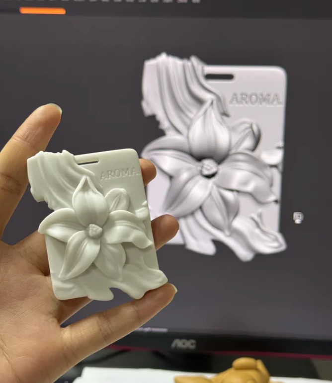 Hand holding custom lily flower plaster diffuser stone with 3D CAD design monitor background