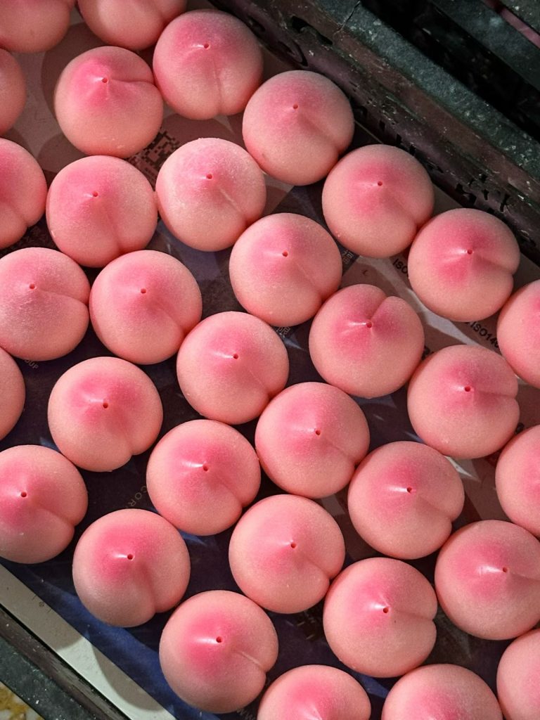 Batch production tray loaded with handcrafted pink peach fruit soy candles in OEM factory
