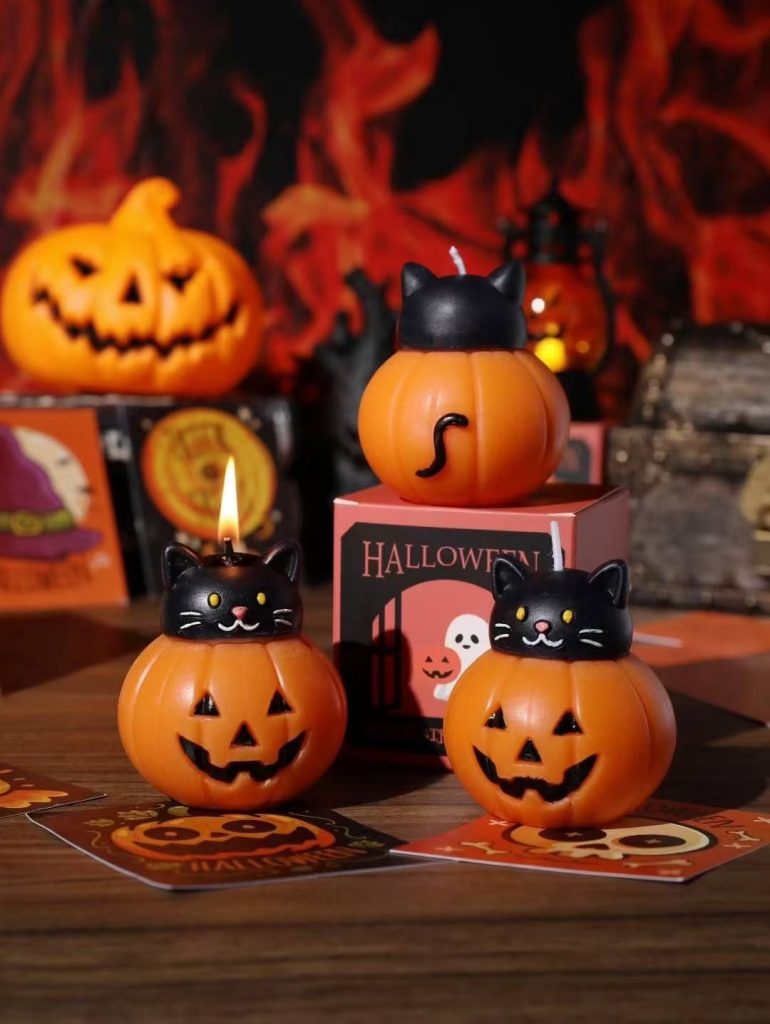 Black cat sitting on orange pumpkin soy candles with custom Halloween packaging