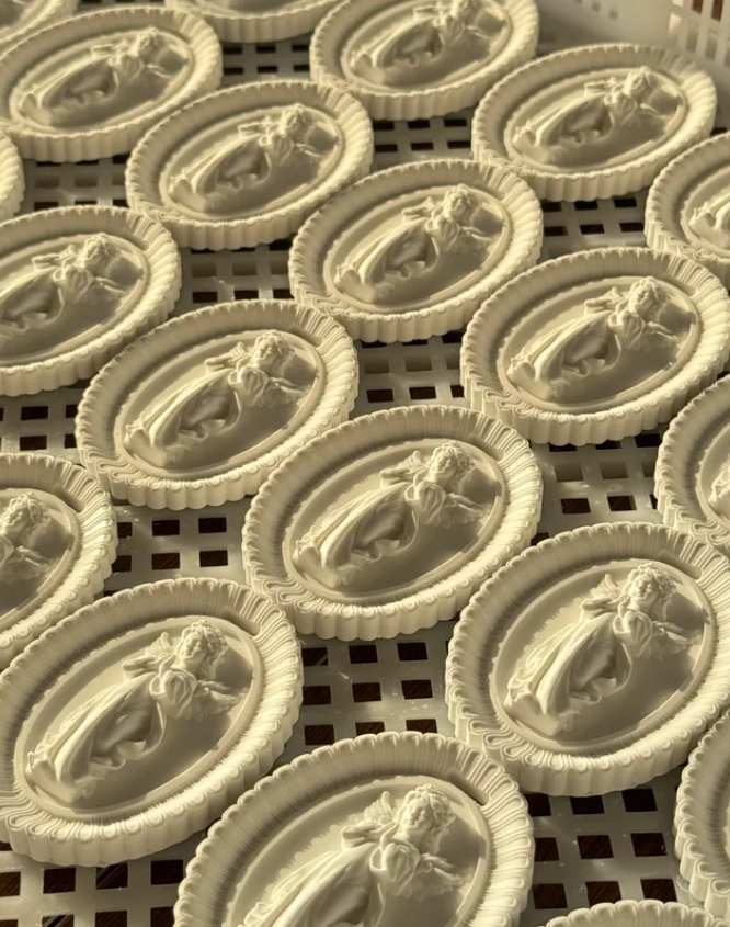 Factory mass production tray of oval angel carved plaster aroma diffuser tablets by Custom Candle Craft