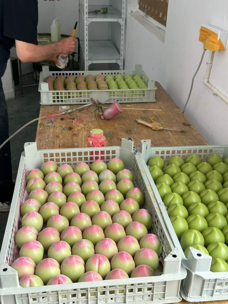 Factory mass production drying racks filled with pink peach shaped soy candles in Custom Candle Craft workshop