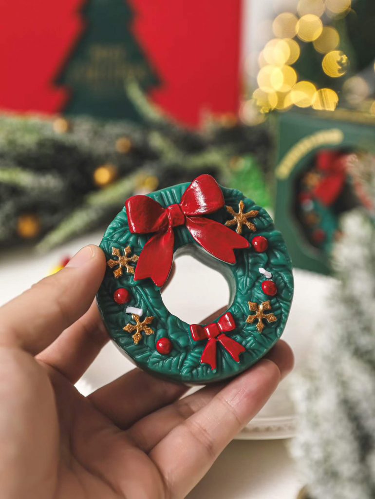 Handheld green and red Christmas wreath soy candle with bow tie manufactured by Custom Candle Craft