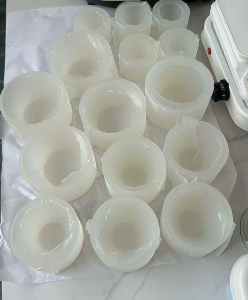 Tray of translucent food-grade silicone cylinder candle molds in manufacturing workshop