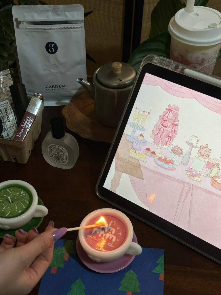 Aesthetic pink latte ceramic cup soy candle burning on a study desk next to coffee accessories for lifestyle home fragrance.