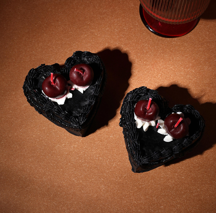 Top view of custom black heart-shaped piped soy wax cake candles with cherry toppers manufactured by Custom Candle Craft factory