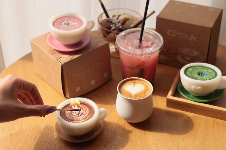 Handcrafted mini ceramic coffee cup scented soy candles with custom kraft packaging boxes on cafe table for wholesale retail.