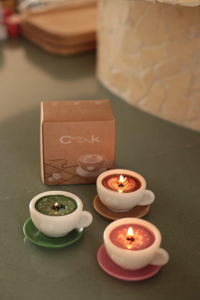 Set of three pastel mini ceramic latte cup candles in matcha green, pink, and caramel with saucers for boutique gift shops.